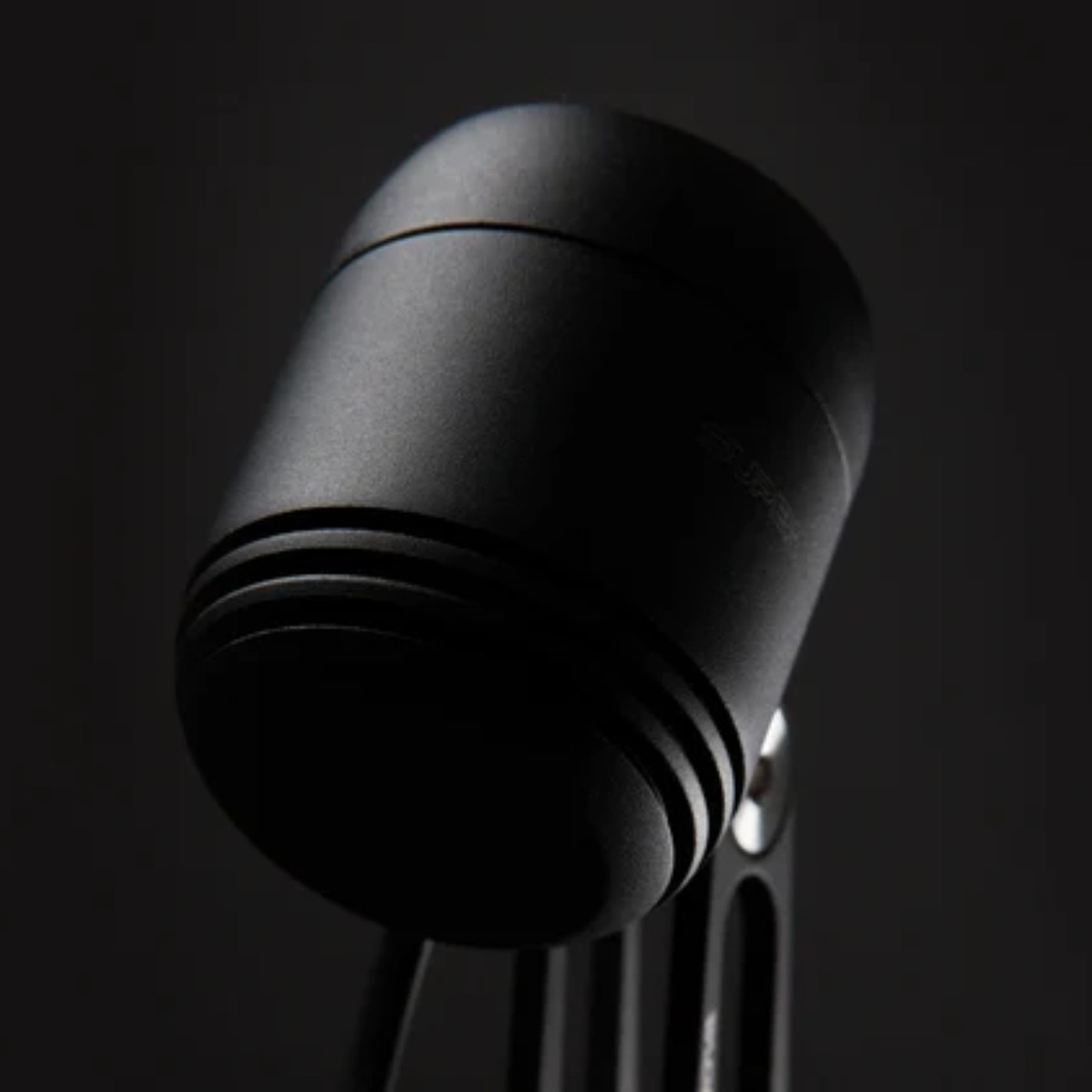Clignotant vélo noir compact, monté sur un support, avec coque ronde et fentes de ventilation visibles sur fond sombre