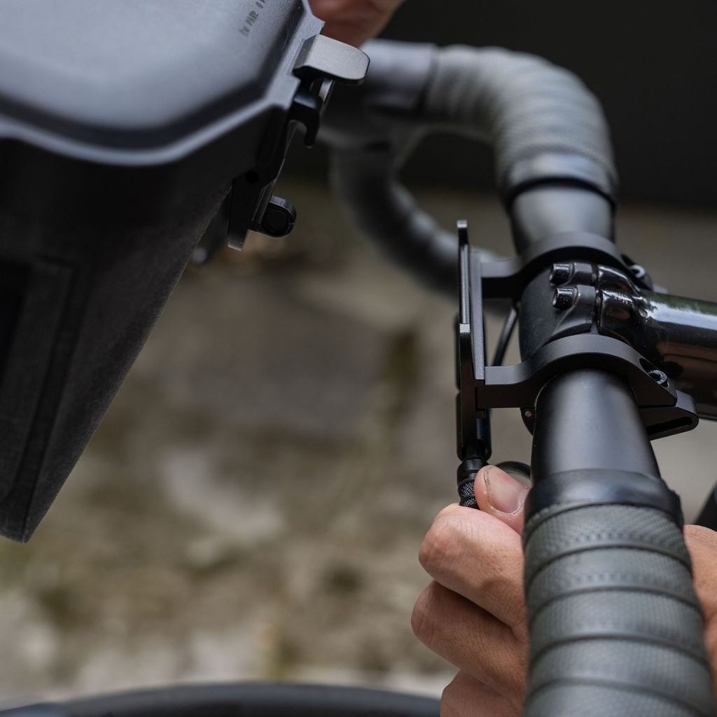 Support de guidon faxation Topeak Fixer 10 sur un vélo, avec un appareil tenu par une main en gros plan