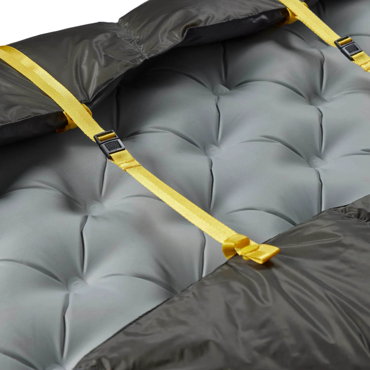 Gros plan d’un matelas gonflable either light sea to summit avec sangles jaunes et boucles de serrage réglables du quilt ember